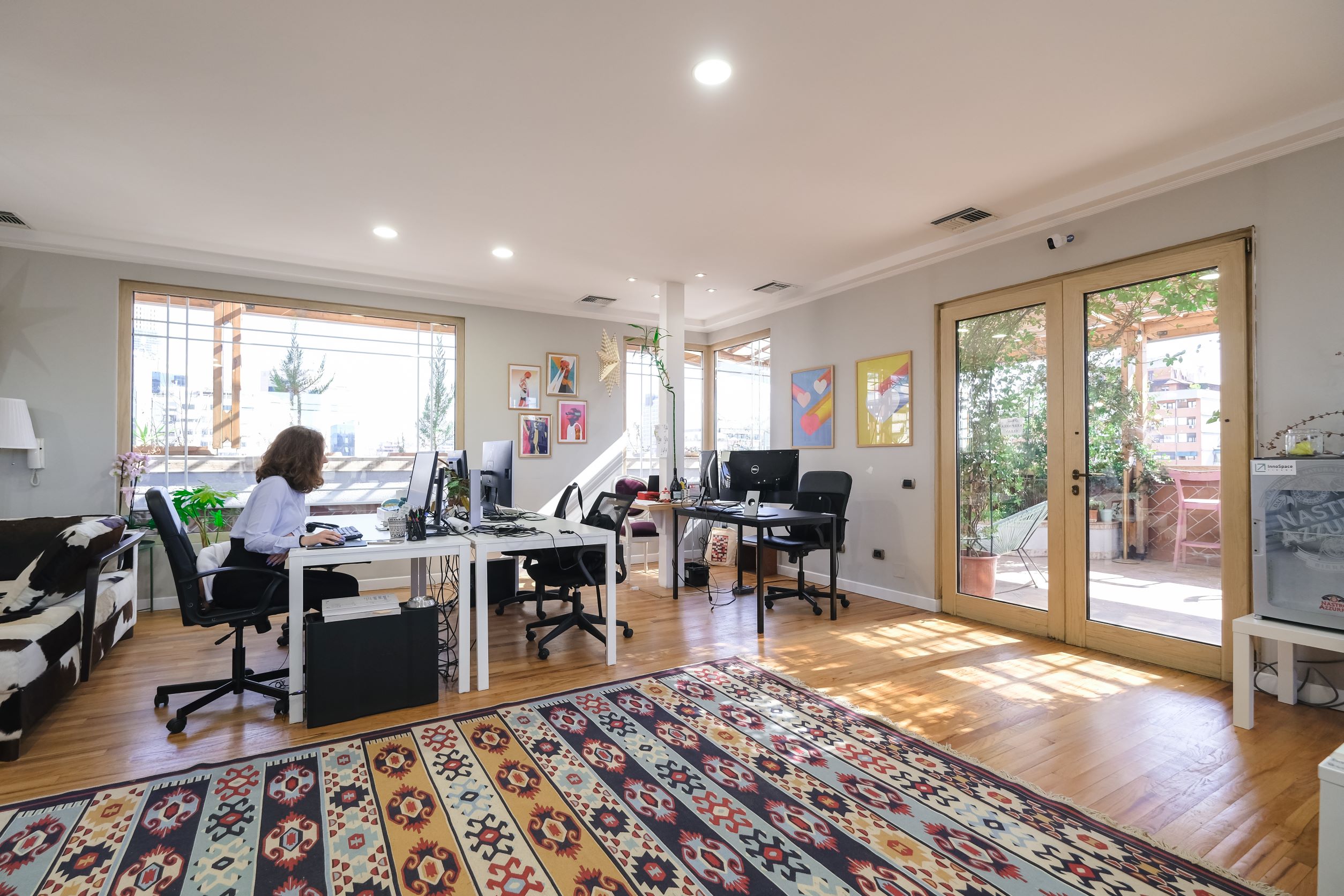 Desks in the shared coworking space at Innospace Tirana, with doors opening onto the balcony